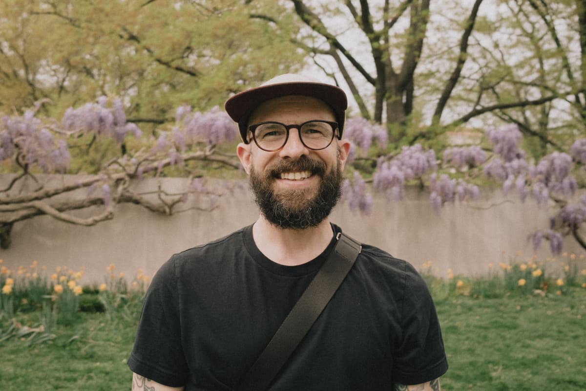 Portrait of me with a beard, wearing a black shirt and glasses, smiling at the camera.
