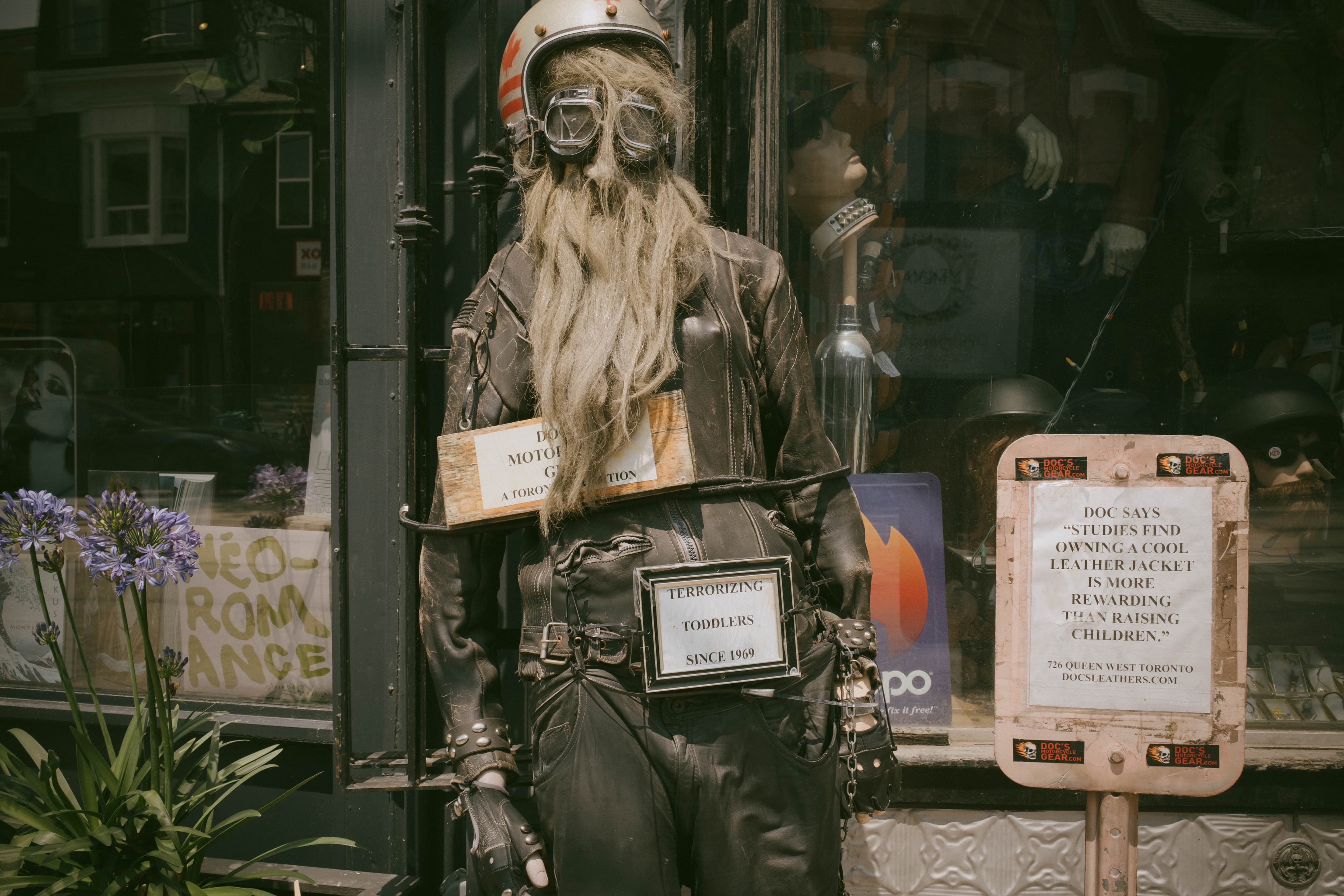 A strange biker-looking mannequin with a sign saying 'terrorizing toddlers since 1969'