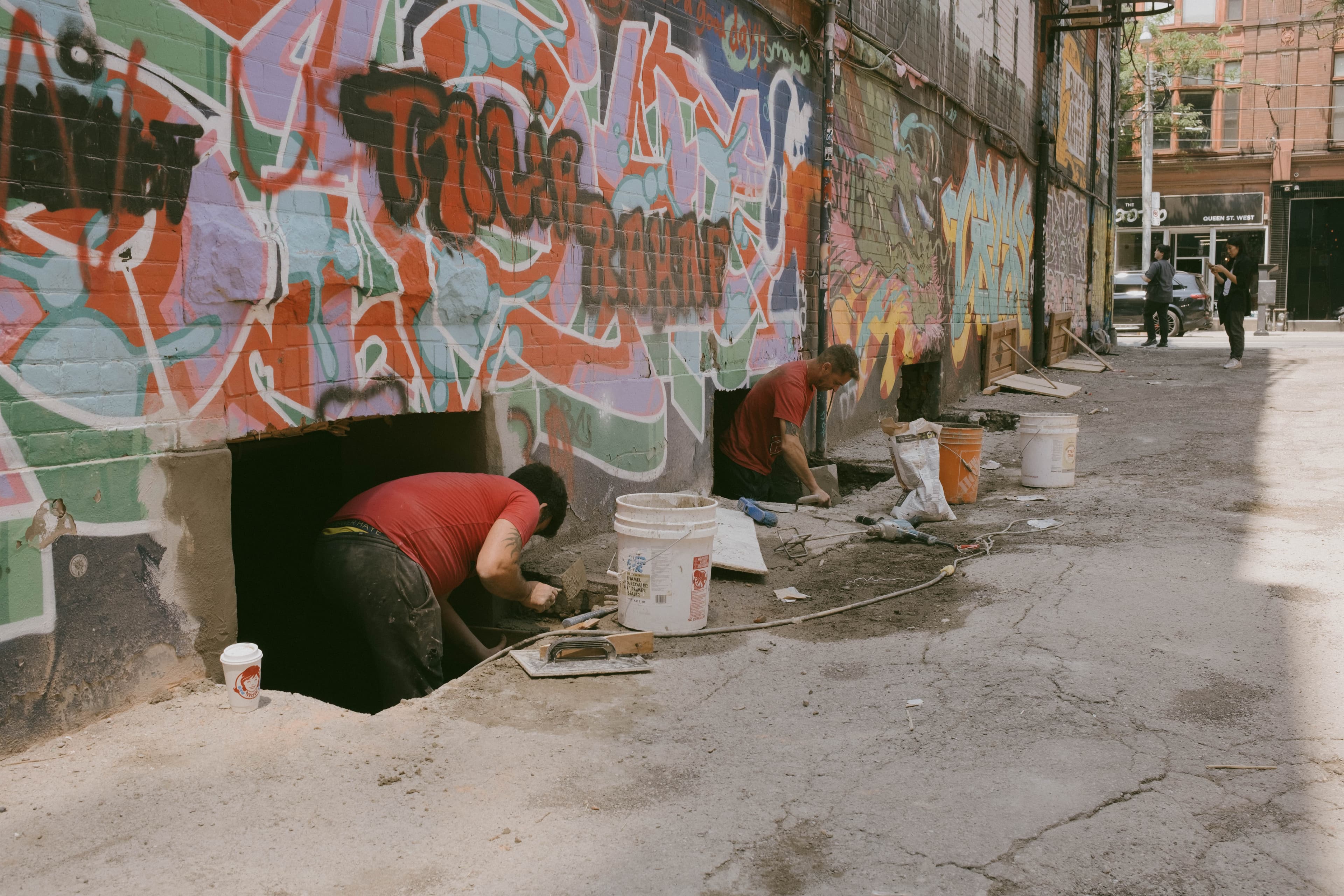 Workers working on egress windows on a heavily painted wall