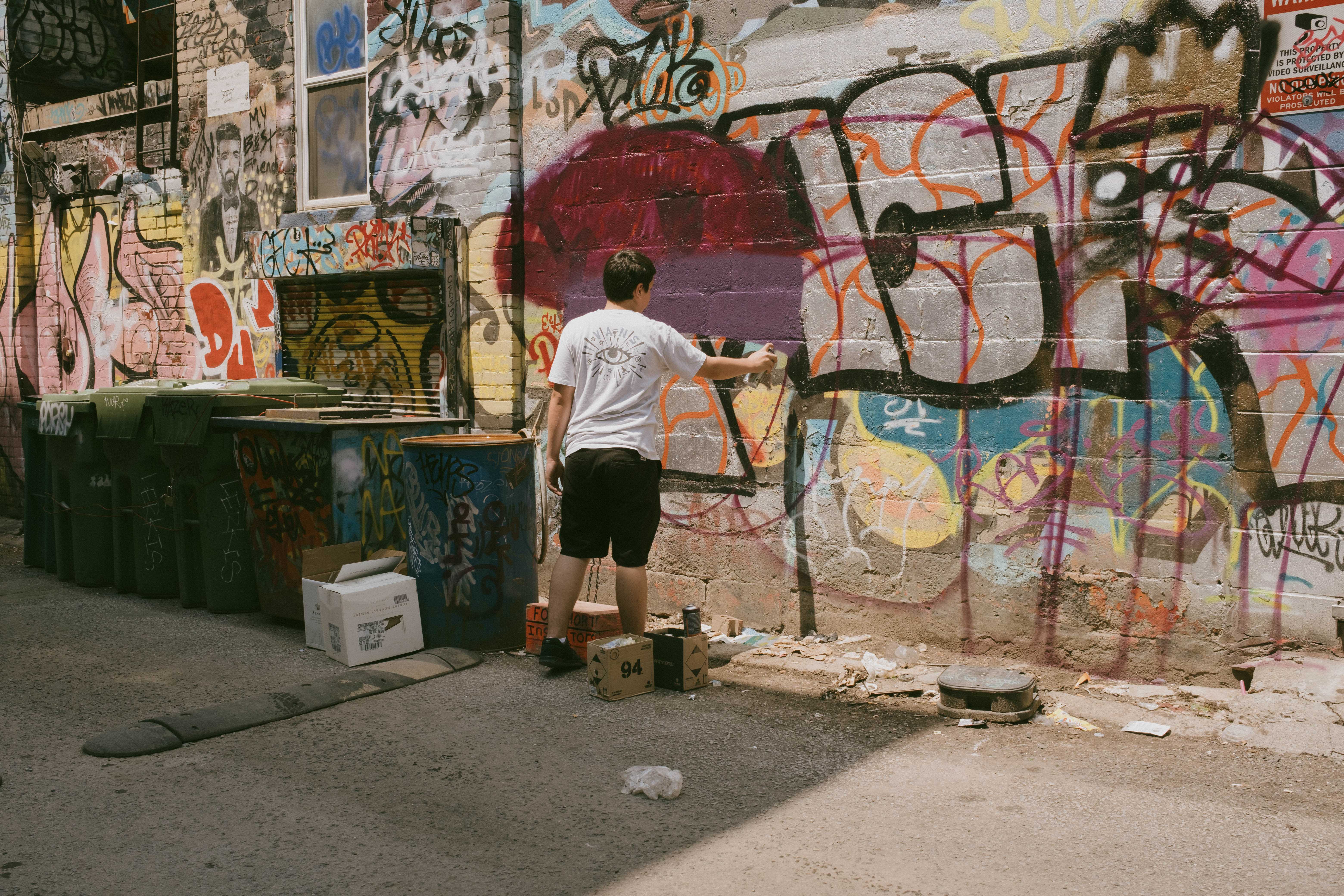 Teenager painting a mural on a spray-painted wall