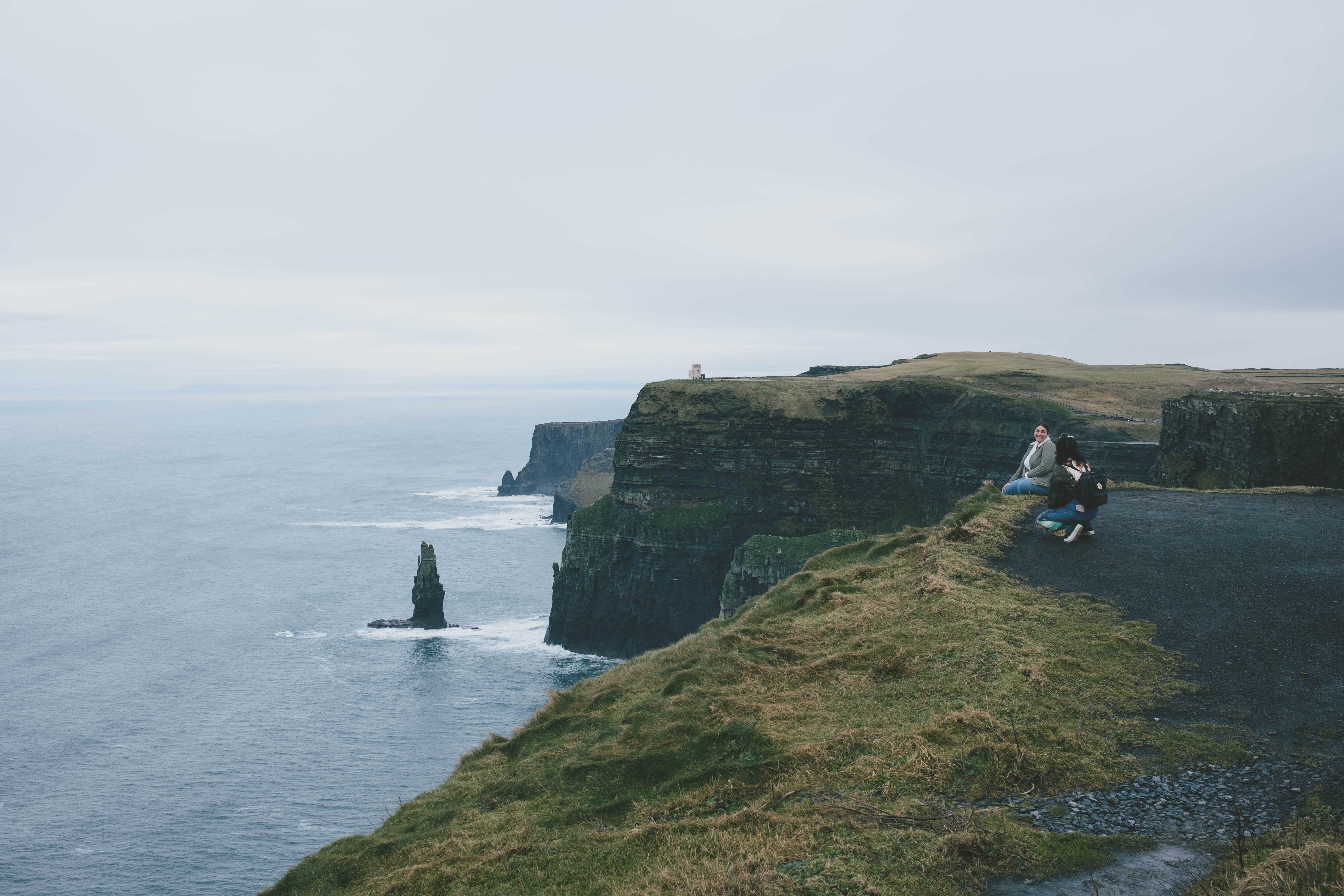 A person posing for a photograph sitting at the edge of the cliff