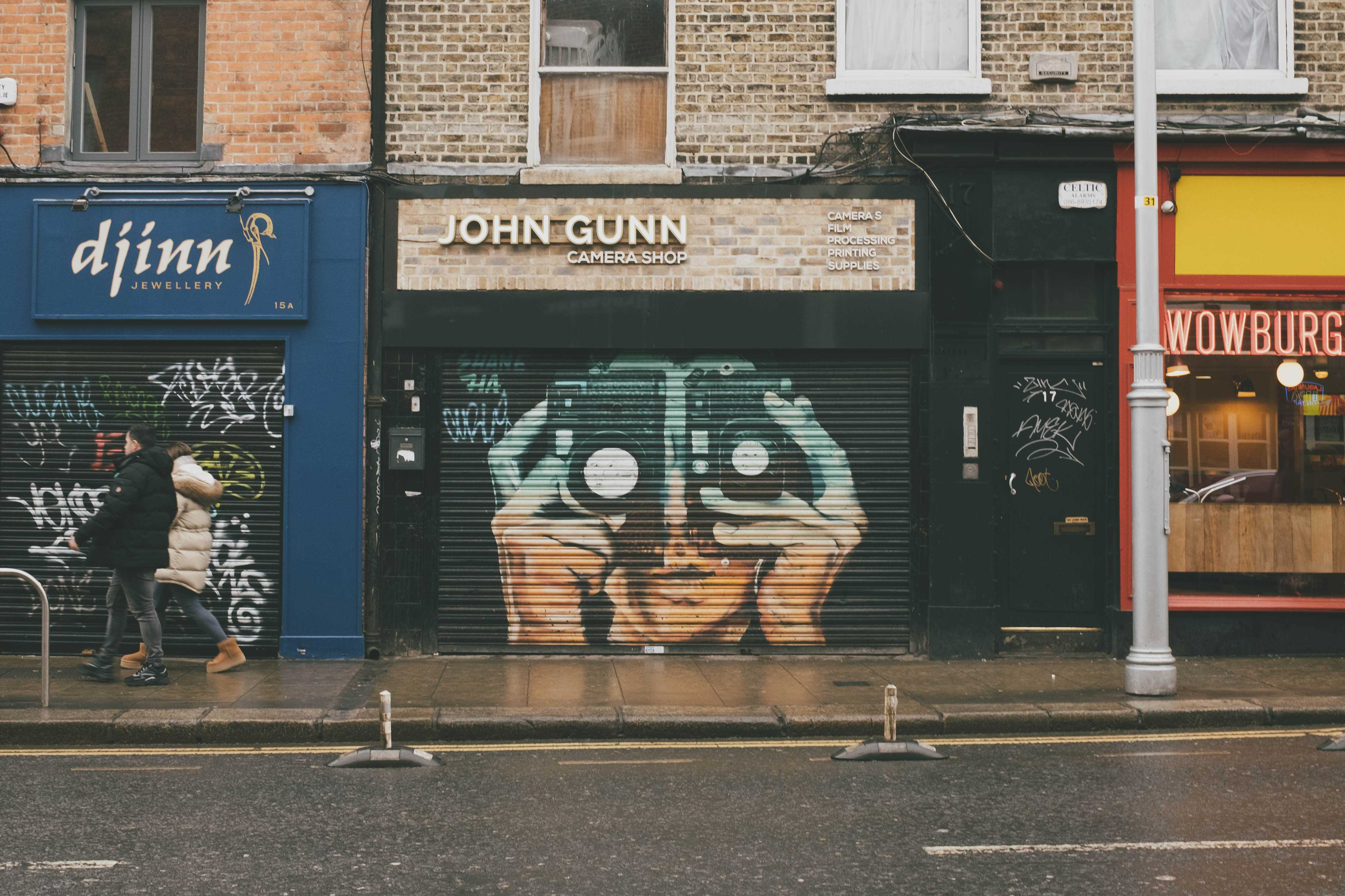 Street art on a camera store with a figure holding two camera, one on each eye.