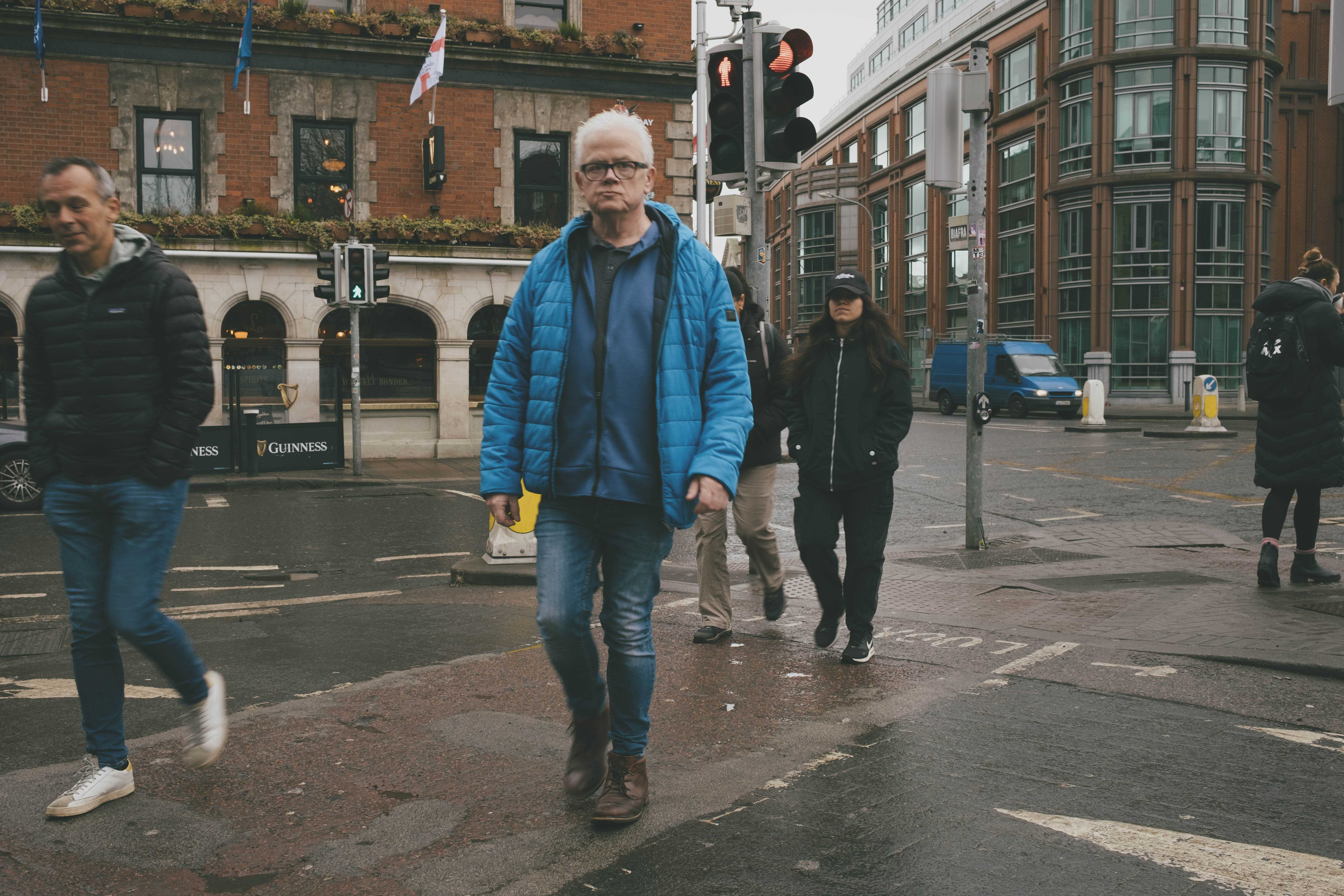 Crowd of people crossing a street, one man looking frumpy