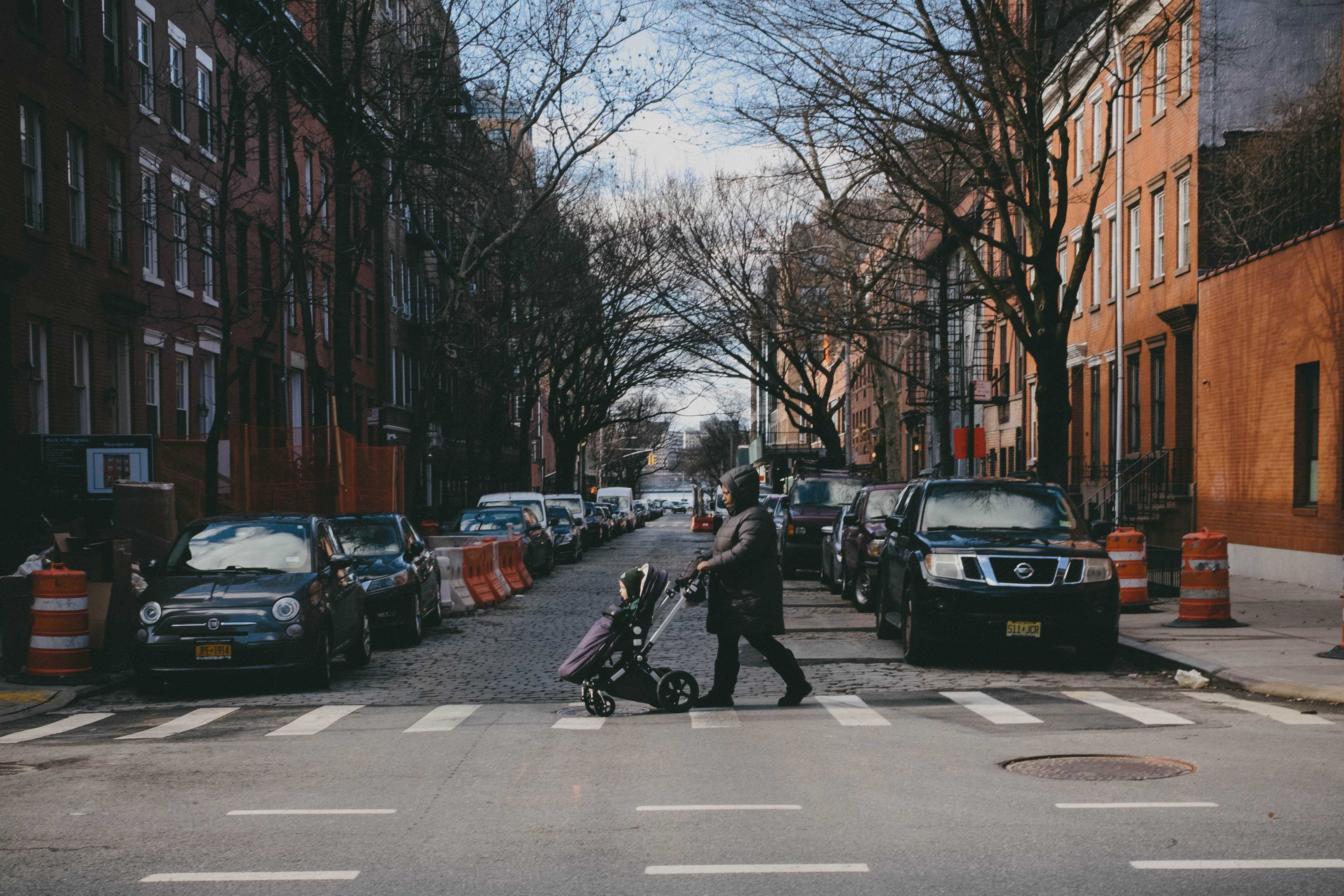 Woman walking a baby in a stroller across the street.