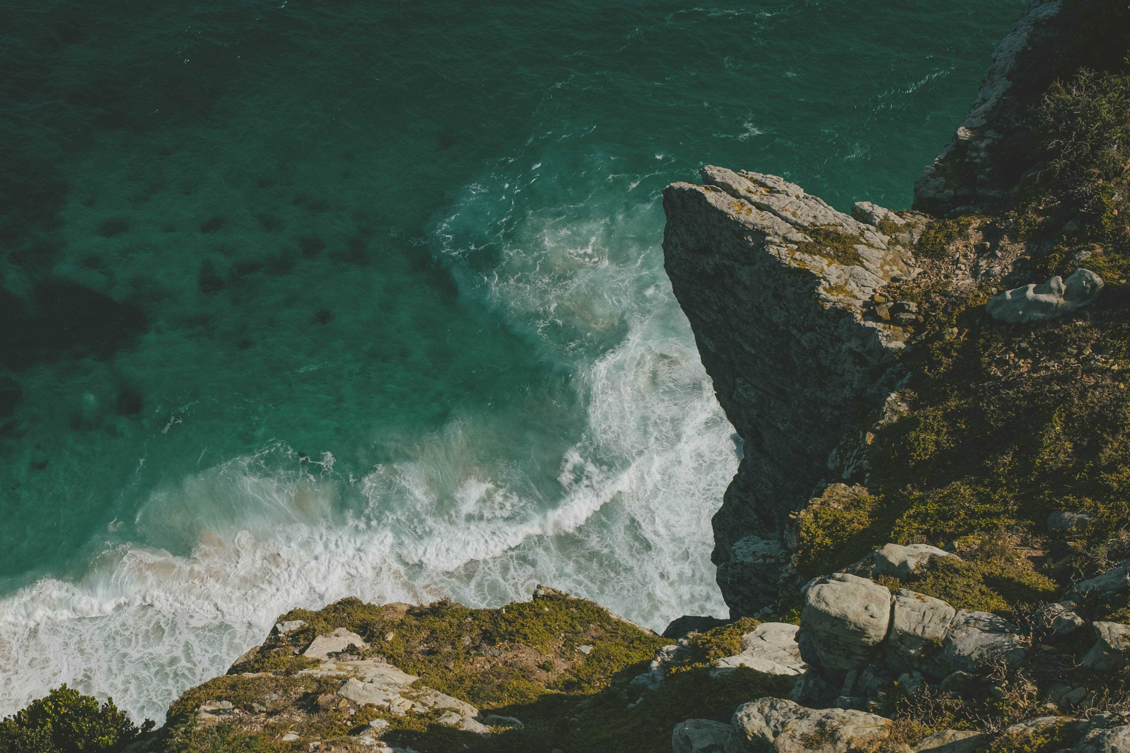 Waves crashing against rocks and the seawall below. A large rock just out in the right hand corner.