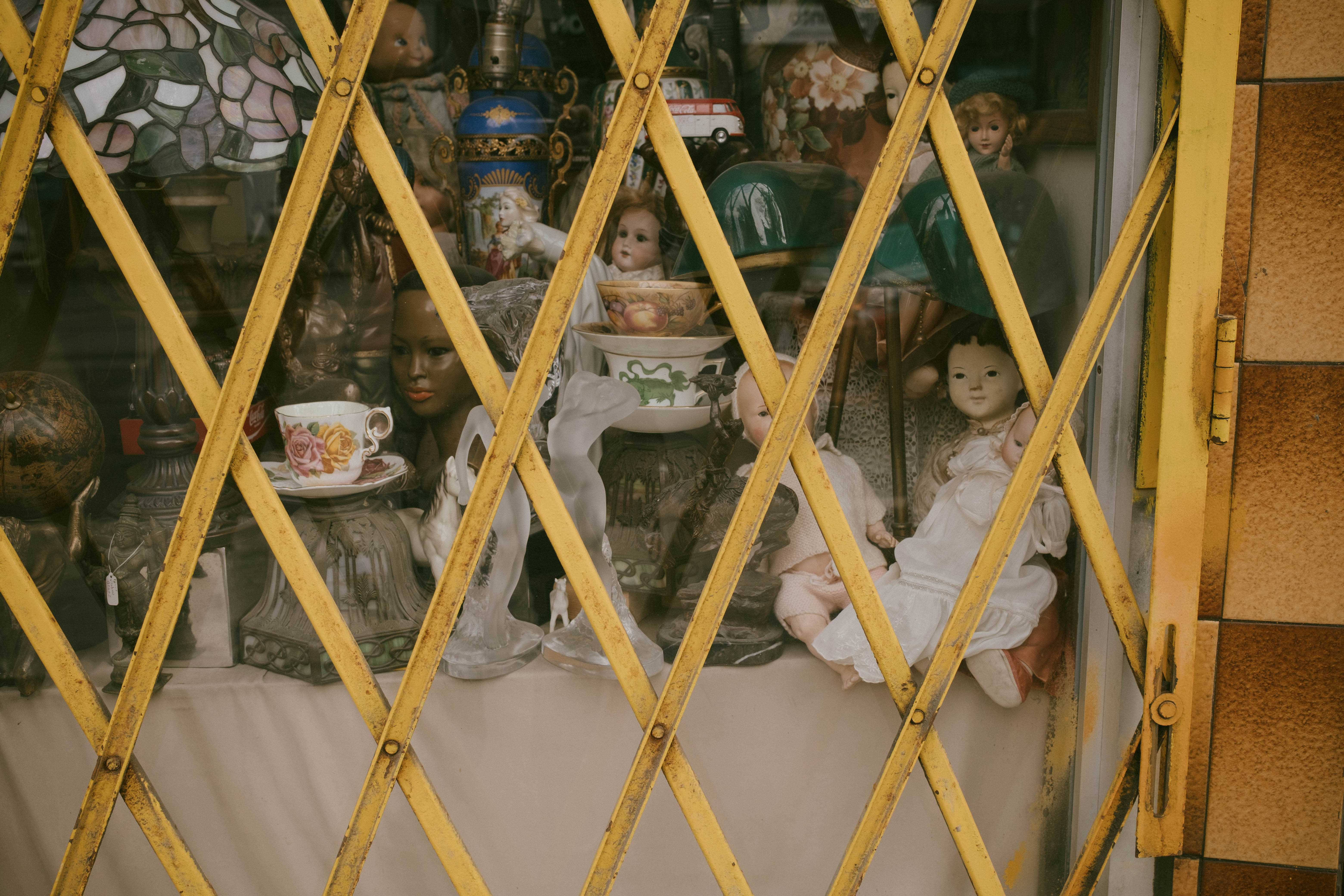 Creepy dolls in a store window hidden behind grates