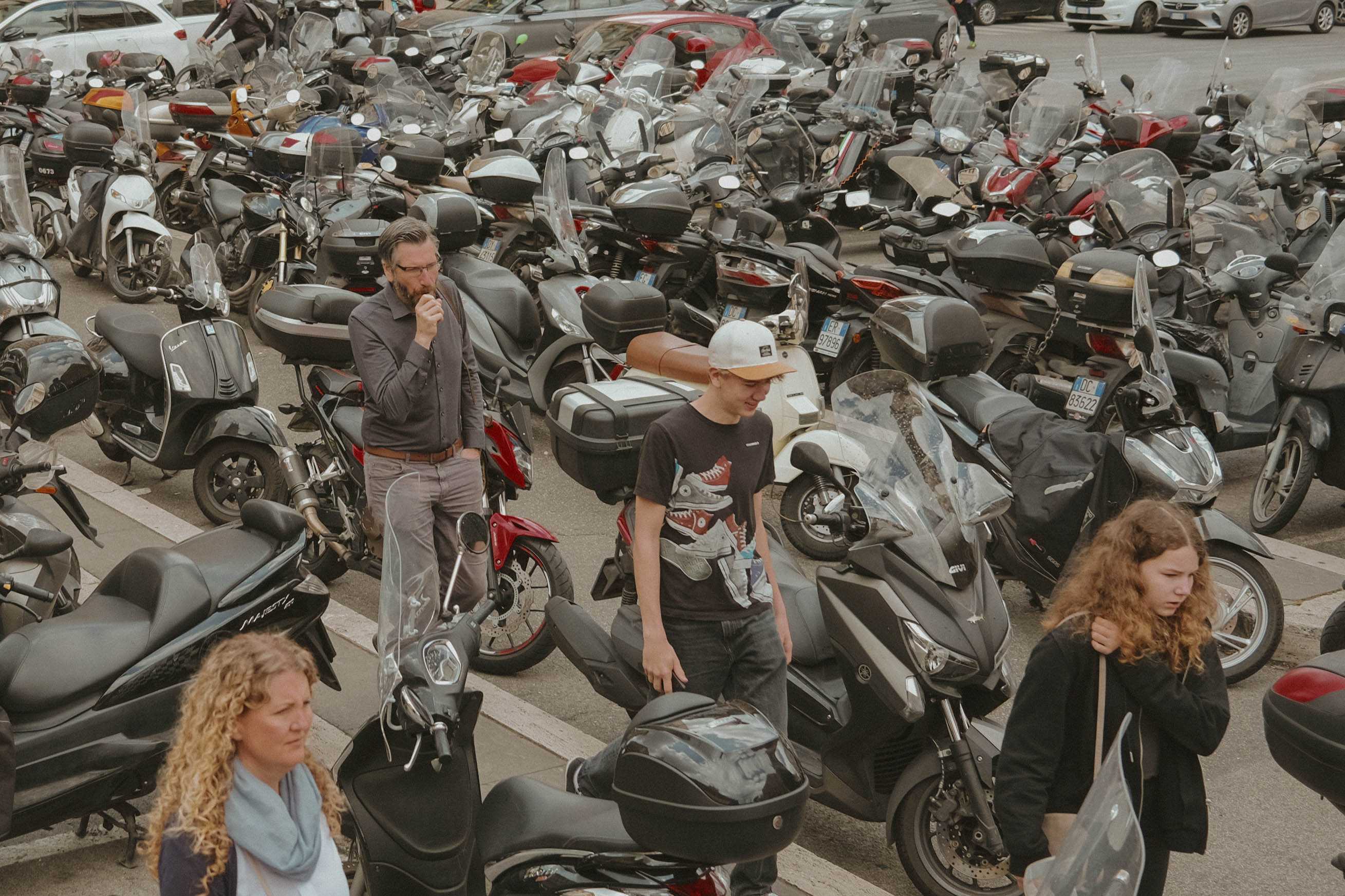 Family walking across a large group of parked scooters