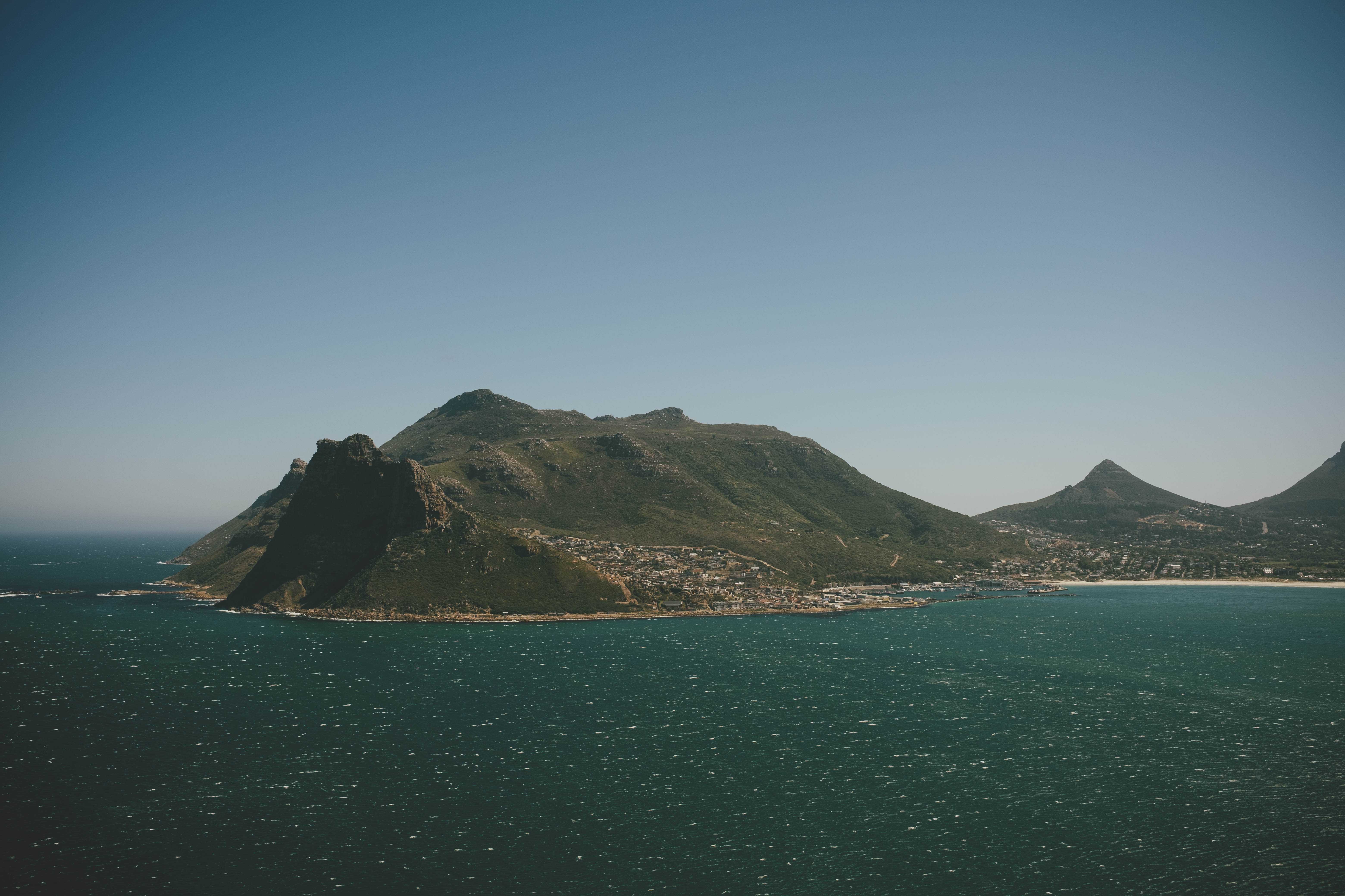 Looking across the choppy waters of Hout Bay, a mountain far off in the distance with houses built up partially along the base