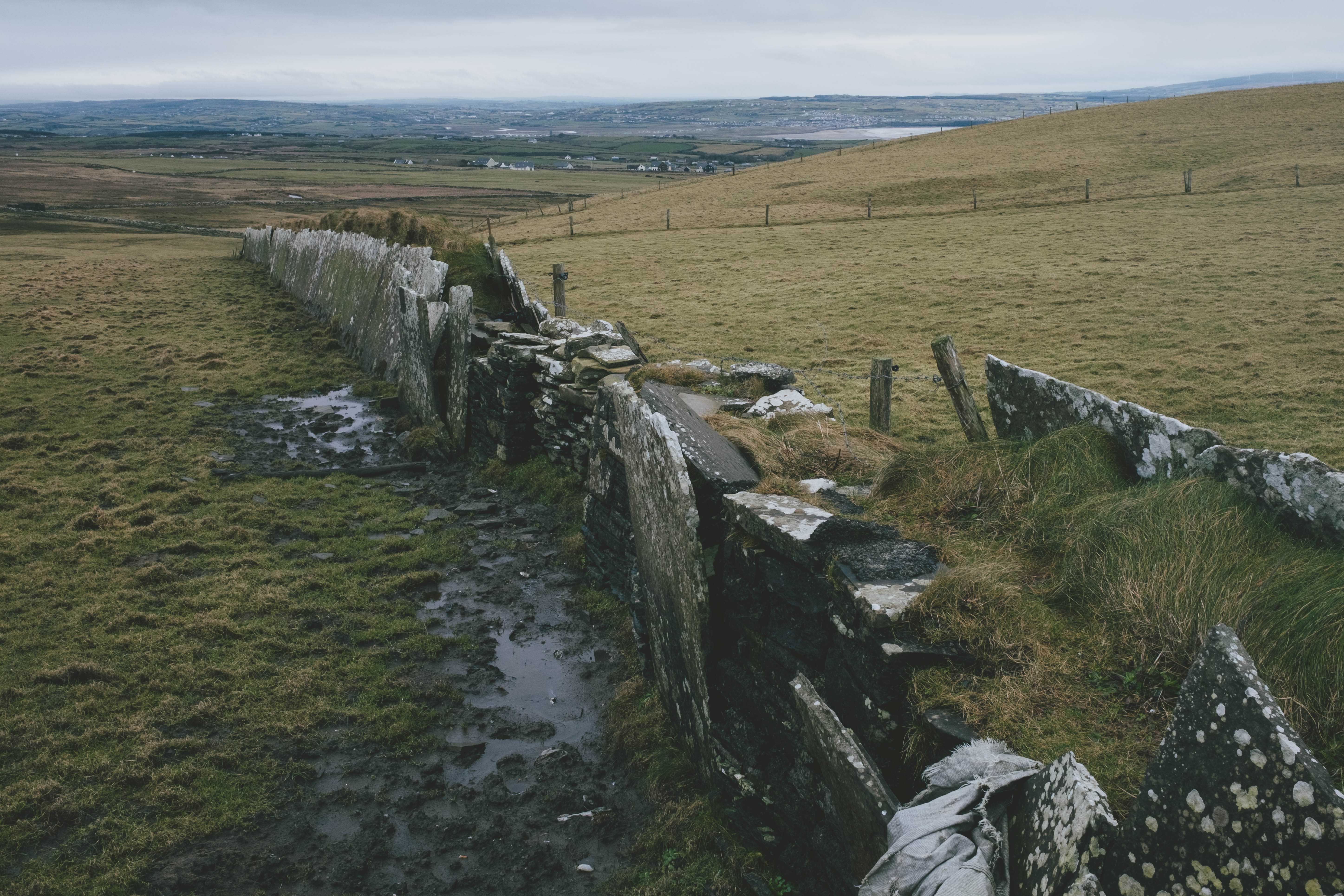 Stone wall in a muddy field with the town distant in the background