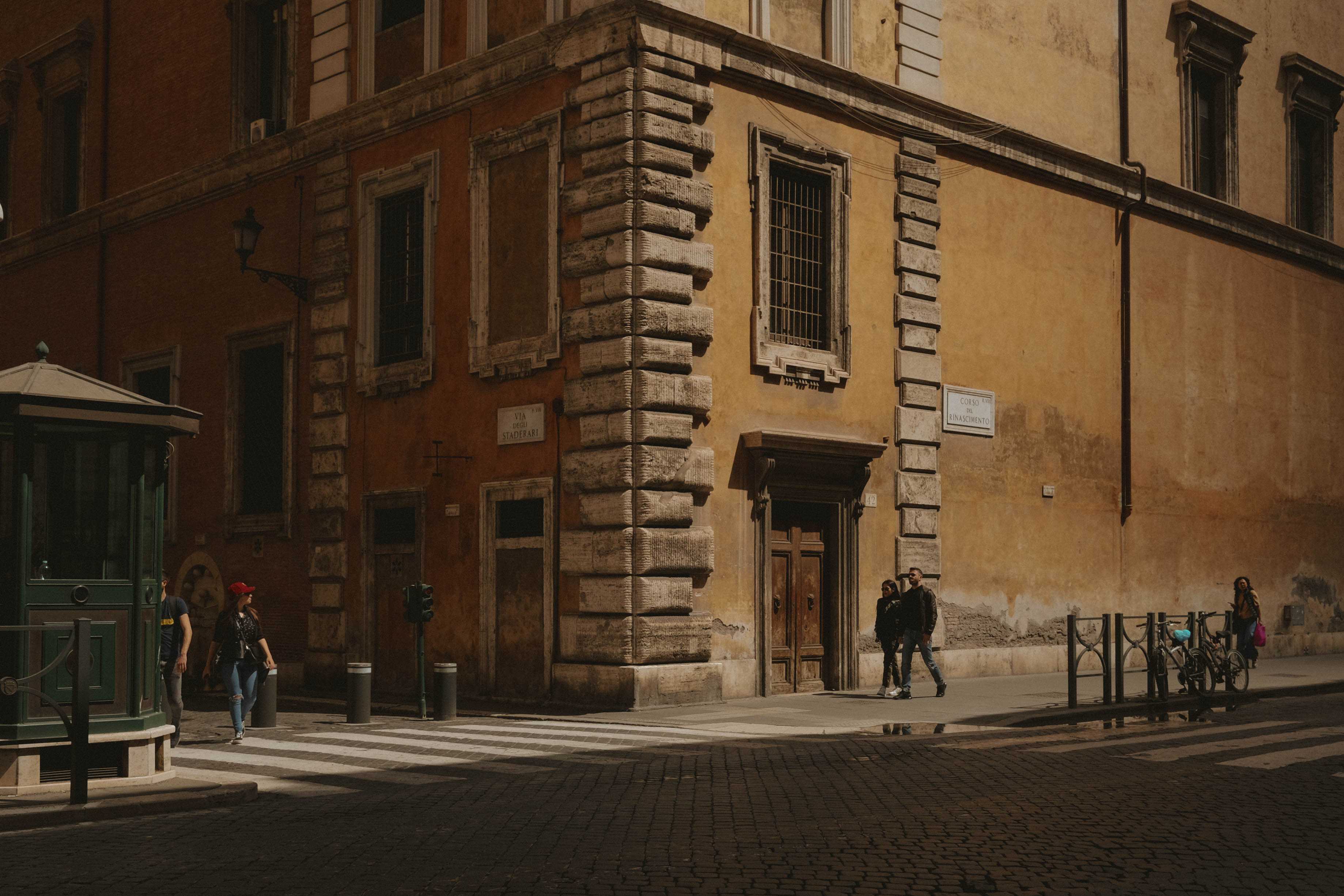 People walking by a government building, dwarfed by its proportions