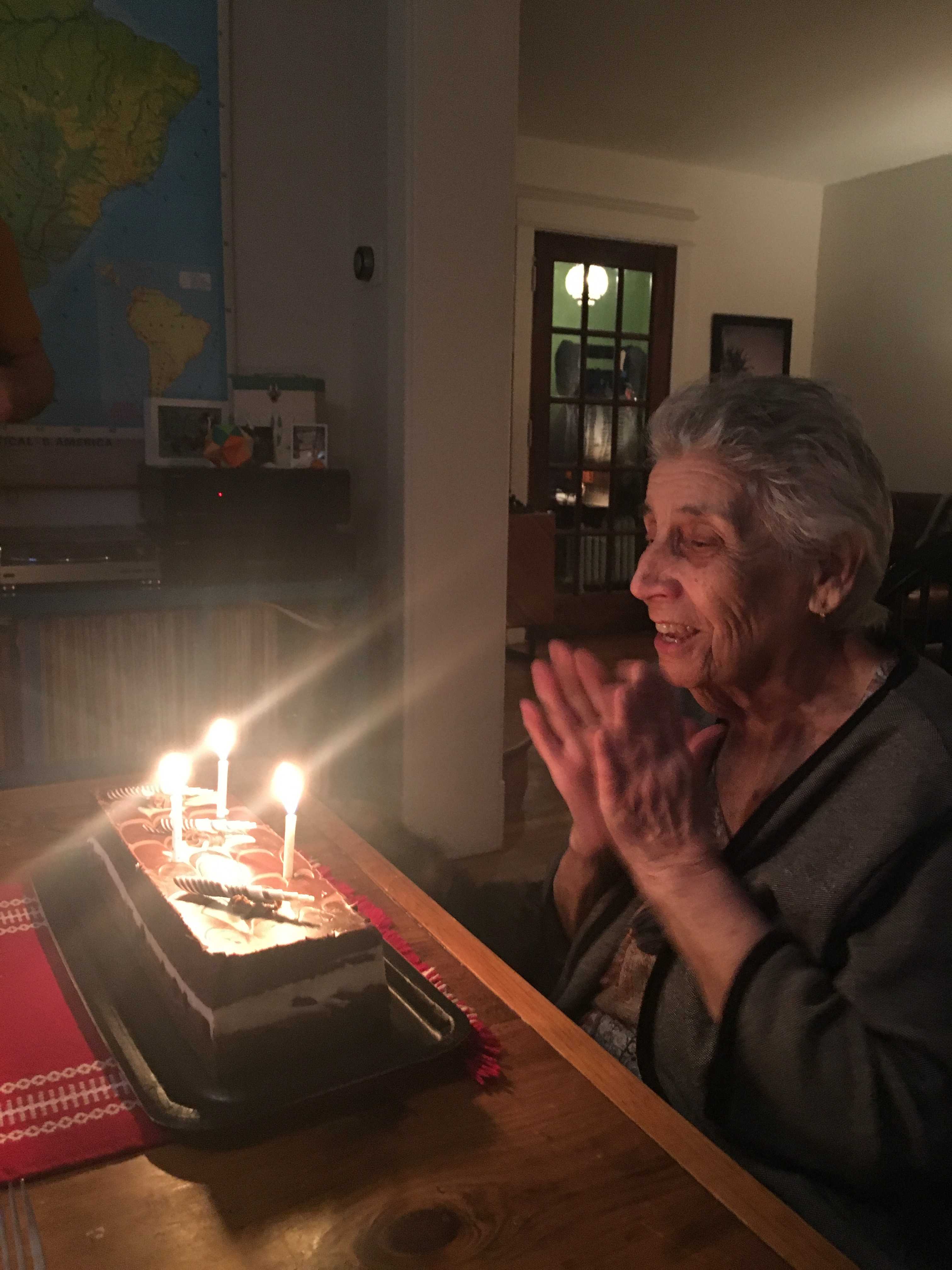 My grandma, clapping and singing in front of her lit birthday cake