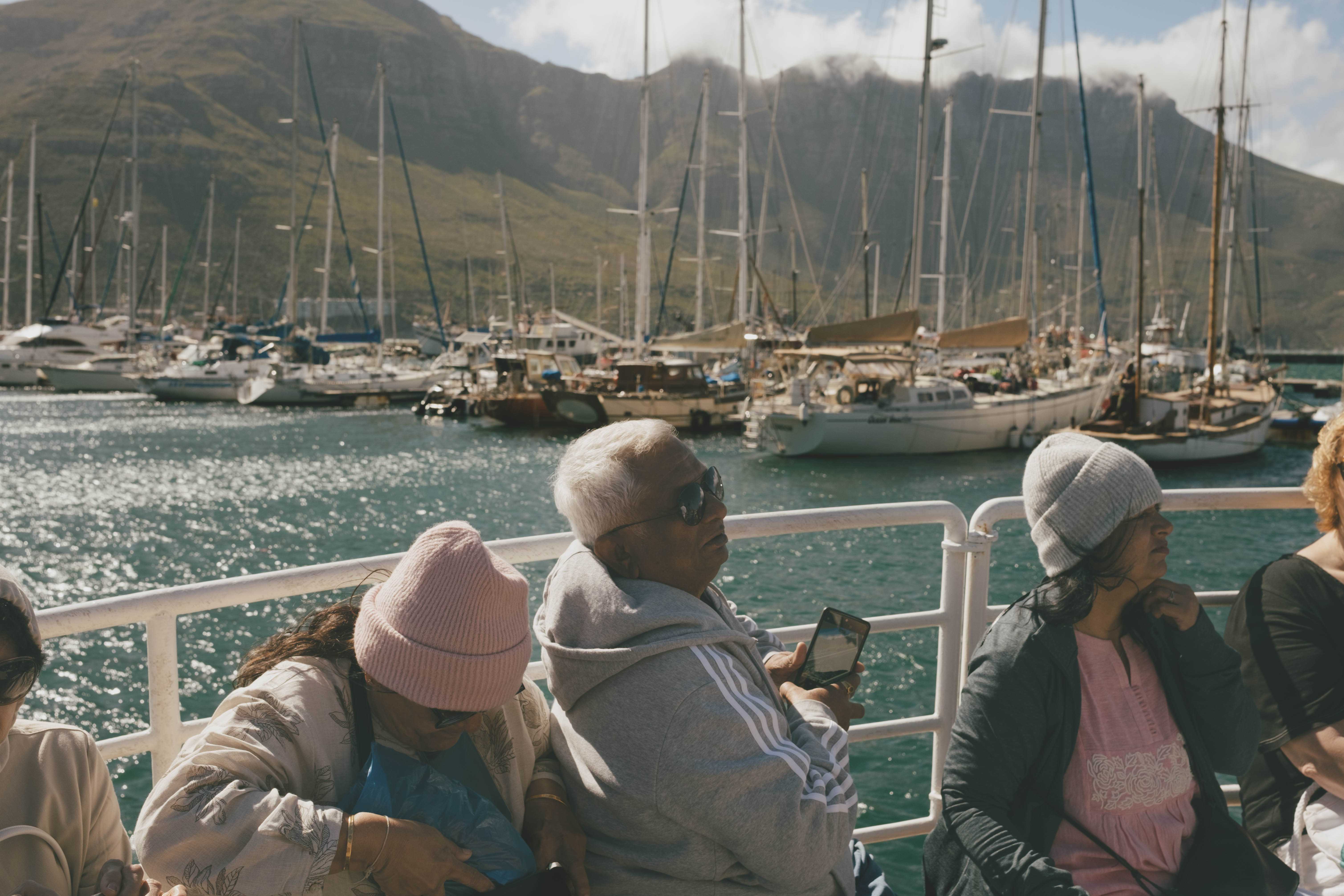 Family sitting on a boat as it leaves the harbor. They appear to be other tourists.