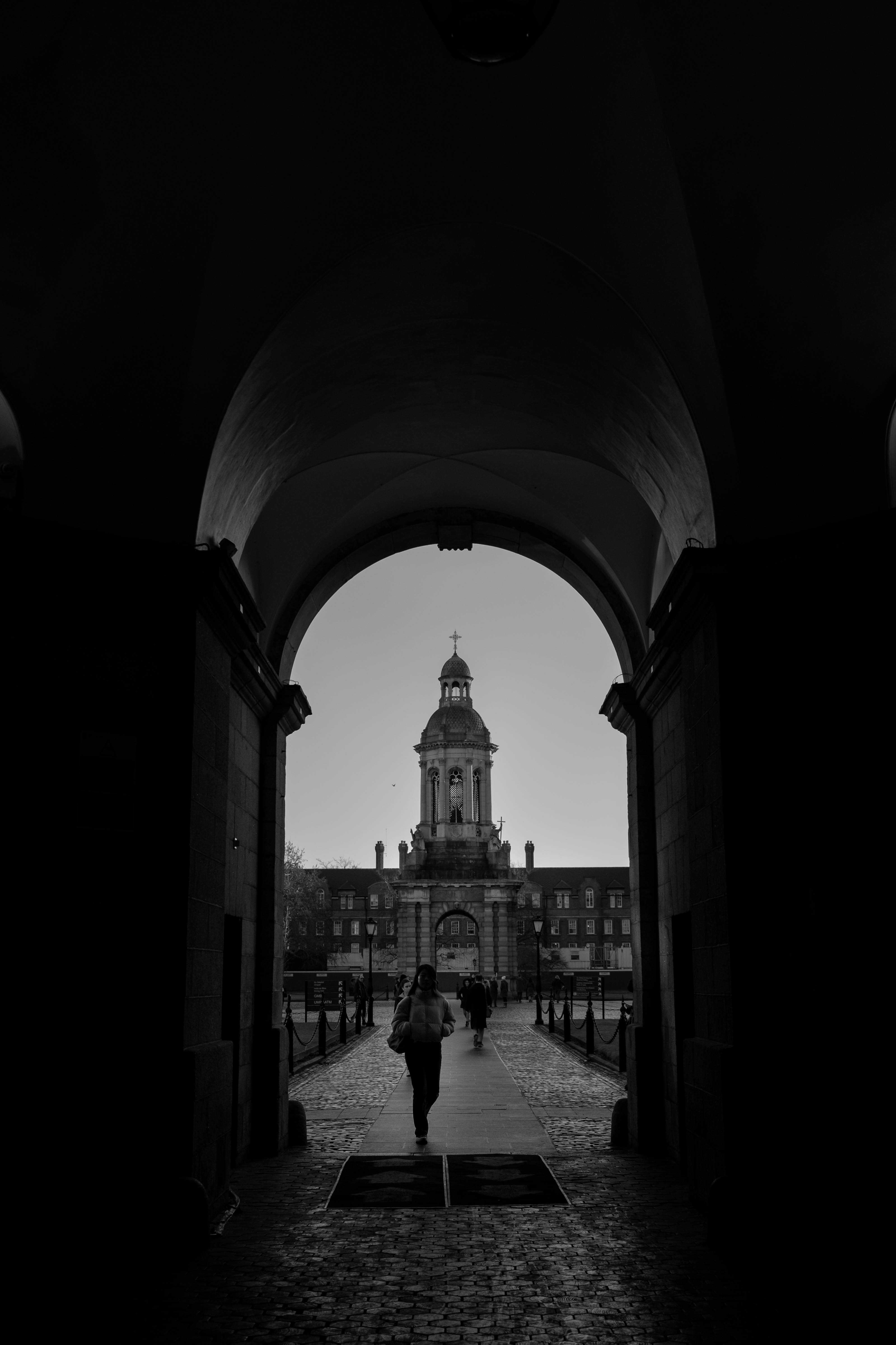 The main entrance gate at Trinity College. A girl is walking through the hallway.