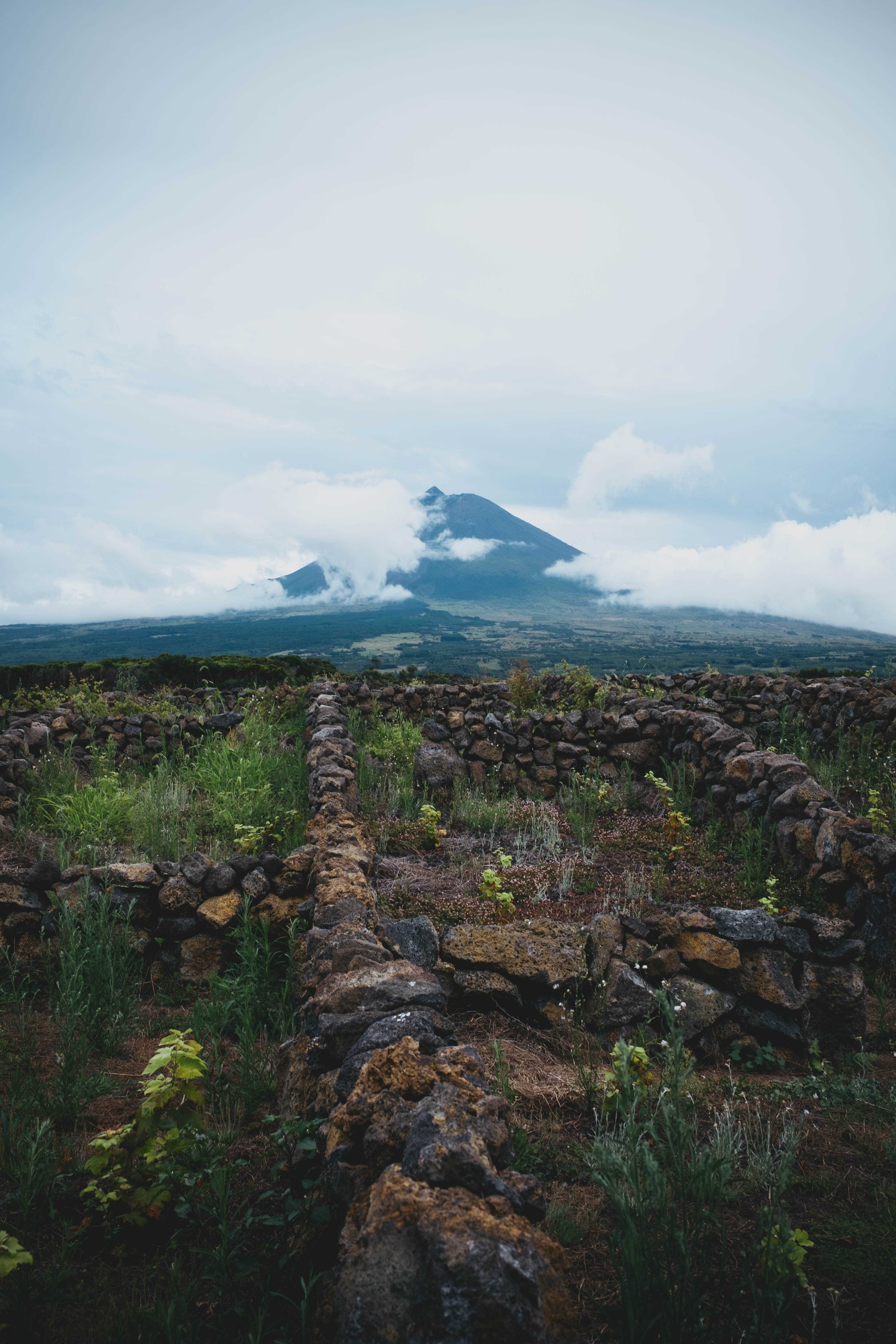 Stacks of volcanic rocks with Mount Pico emerging from the clouds in the background.