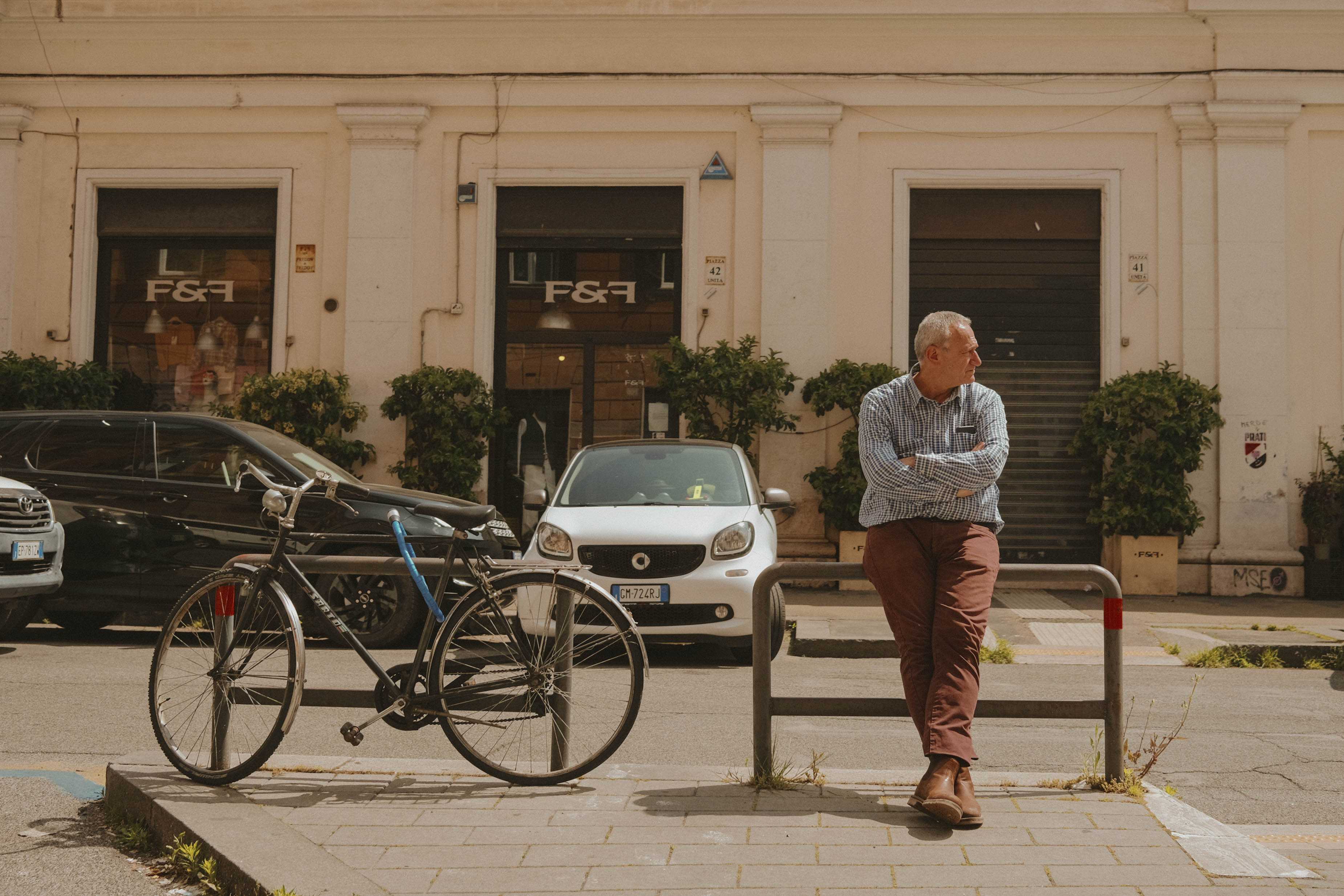On the left, a bicycle. On the right, an older man leaning against a bike rake, looking in the opposite direction of the bike.
