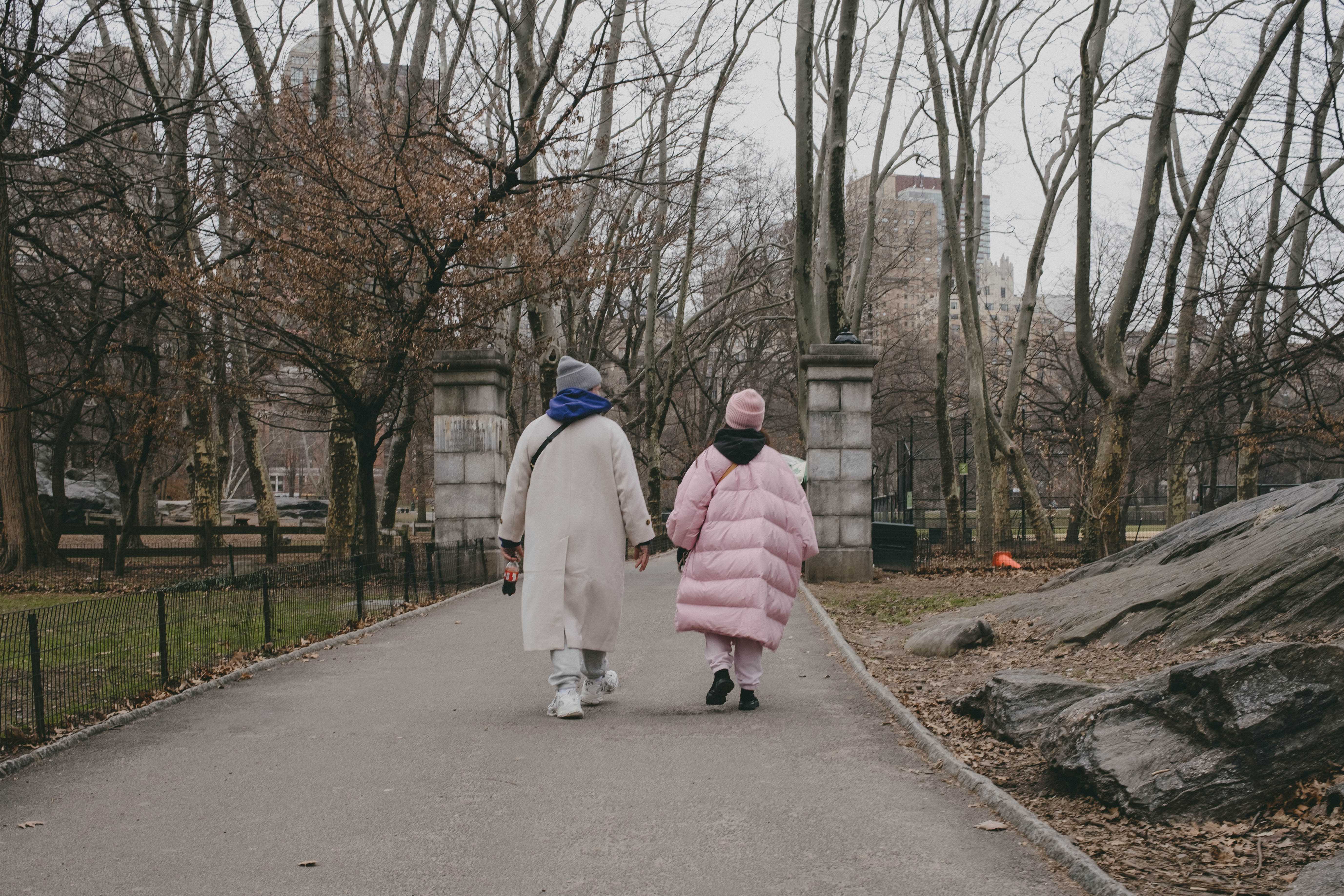 A couple with long, oversized and puffy coats walking alone on a path in Central Park