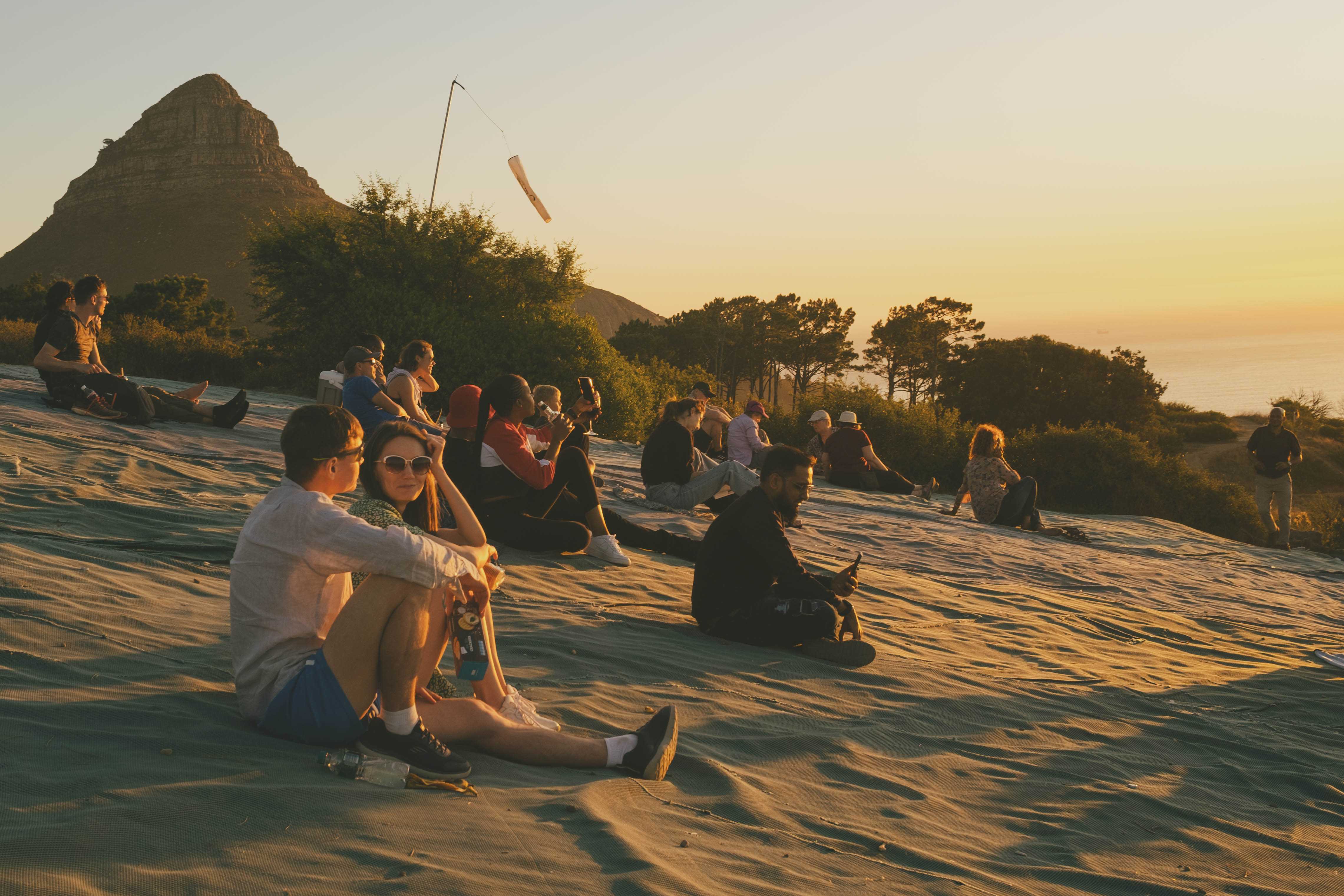 People watching the sunset on a slope with Lion's Head Mountain in the background