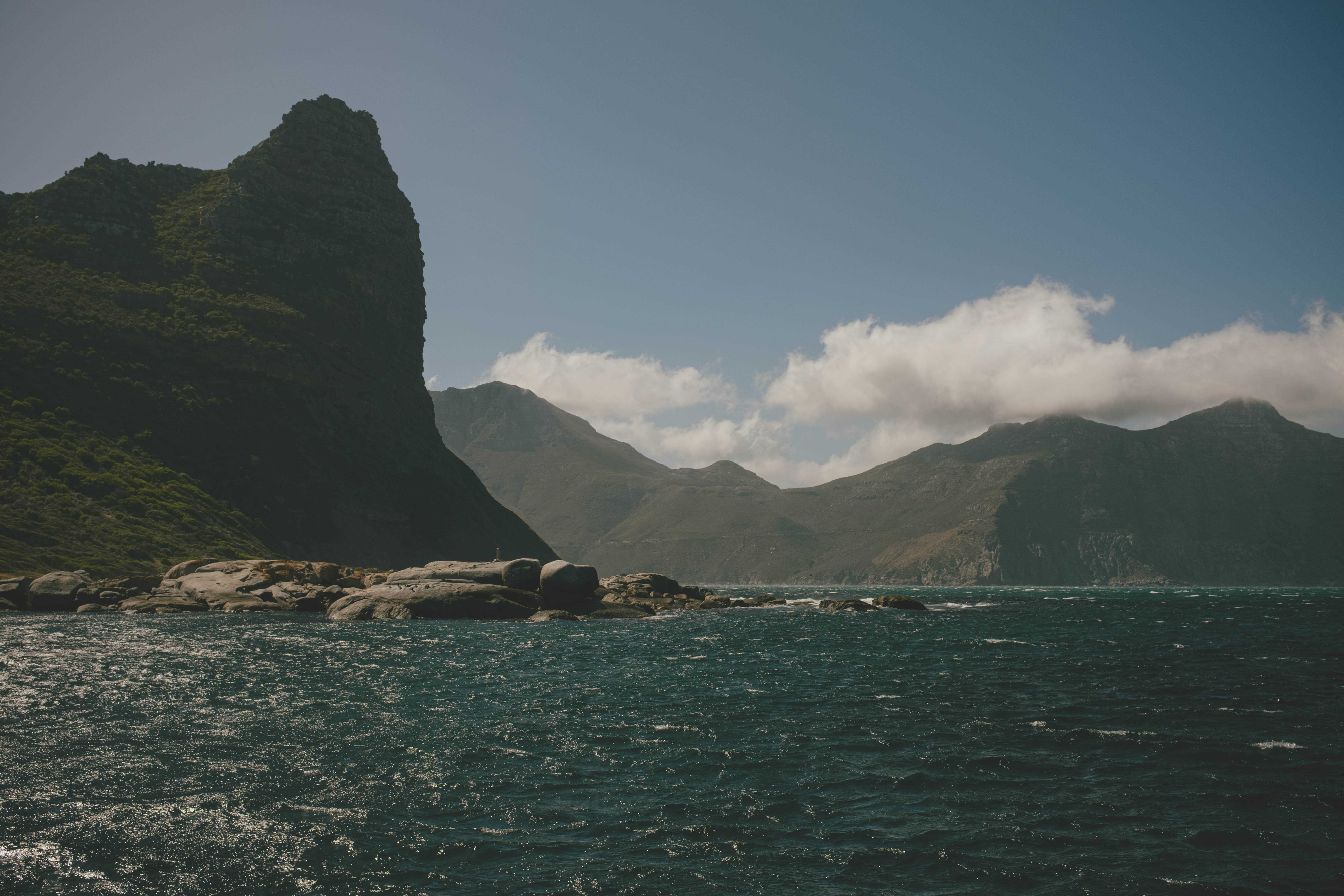 Looking back at Hout Bay from the water. Mountains with a a few clouds in the background.